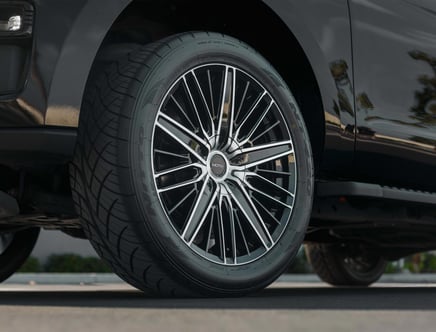 Close-up of a car wheel with a sleek, multi-spoke alloy rim and a high-performance tire on a black vehicle.