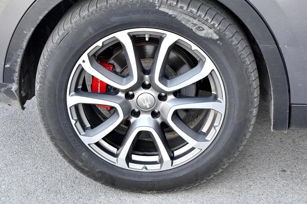 A tire on a vehicle with tread separation at the 10 o'clock position, just beneath the shoulder of the tire.