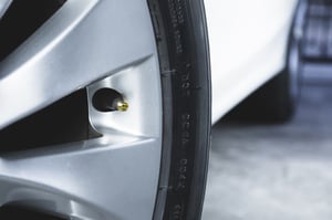 Close-up view of a car tire's rim with a visible air valve stem.
