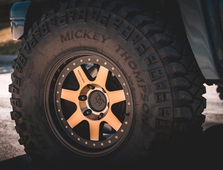 Close-up of a rugged Mickey Thompson tire on a vehicle, featuring prominent tread patterns suitable for off-road driving.