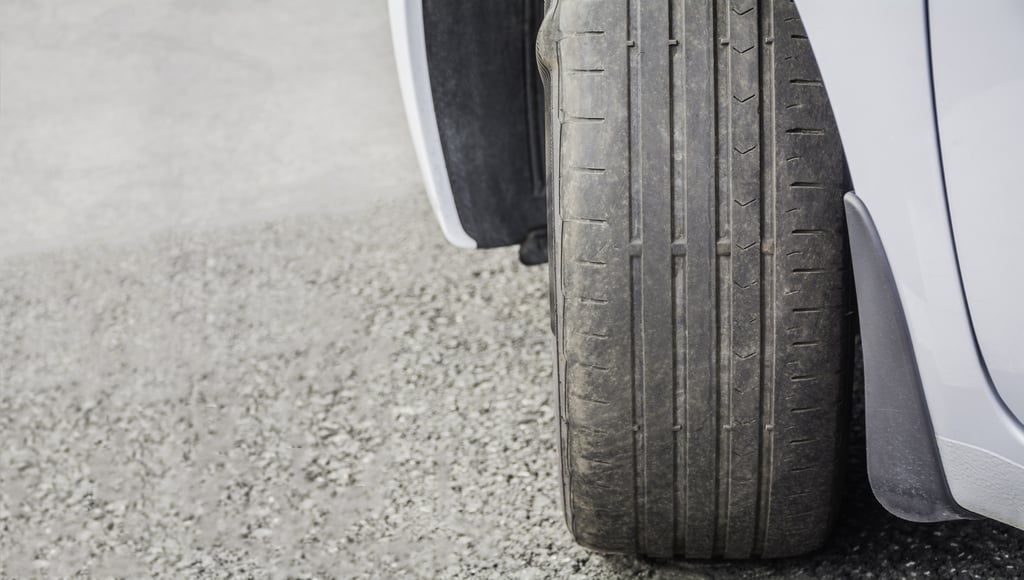 a close up of a driver's side front tire showing that the tread is level with the tire bars, which means it is time to replace these tires.