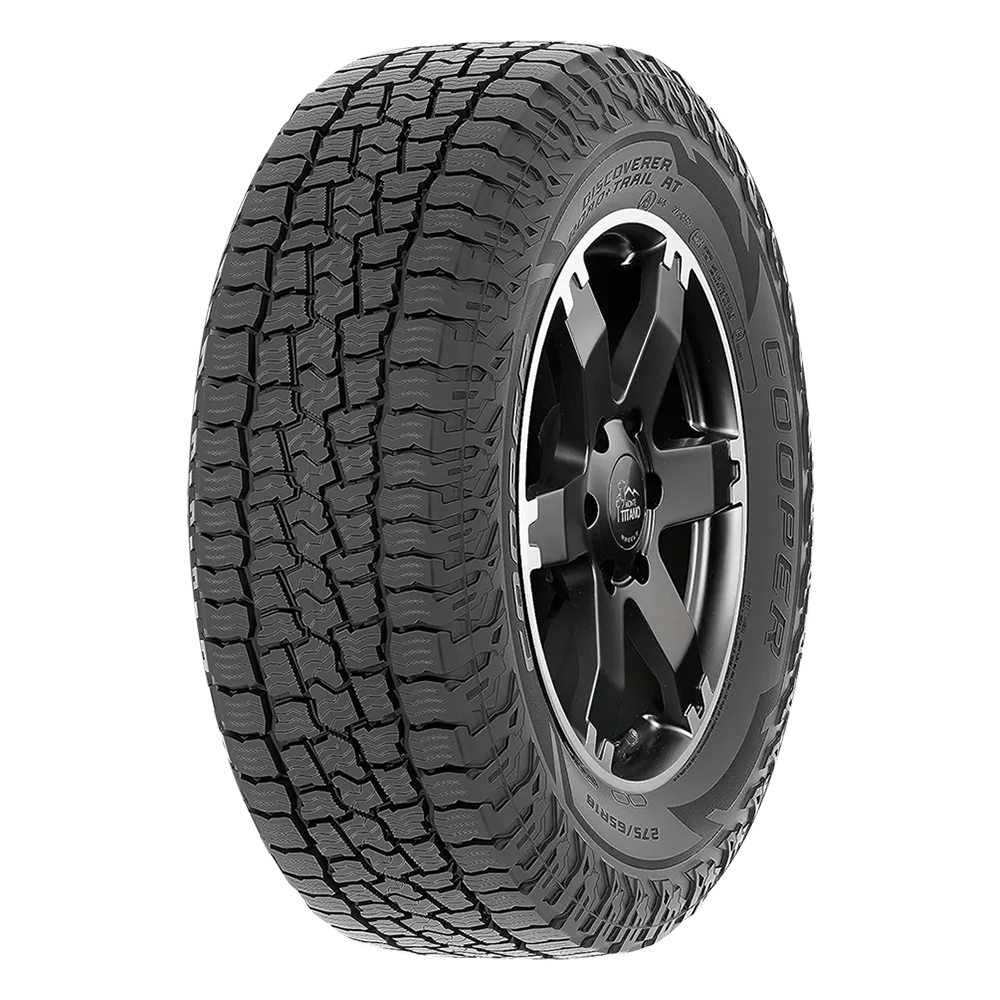 A black Cooper Discoverer Rugged Trek tire with a detailed tread pattern and a modern wheel design, shown on a transparent background.