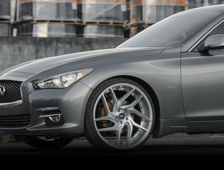 Close-up of a sleek, gray car with large alloy wheels and a badge reading '3.7' on the fender.