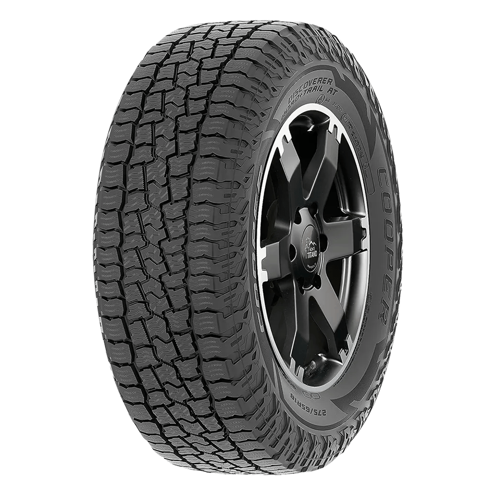 A rugged all terrain tire by Cooper Discoverer Road + T mounted on a black and silver wheel.