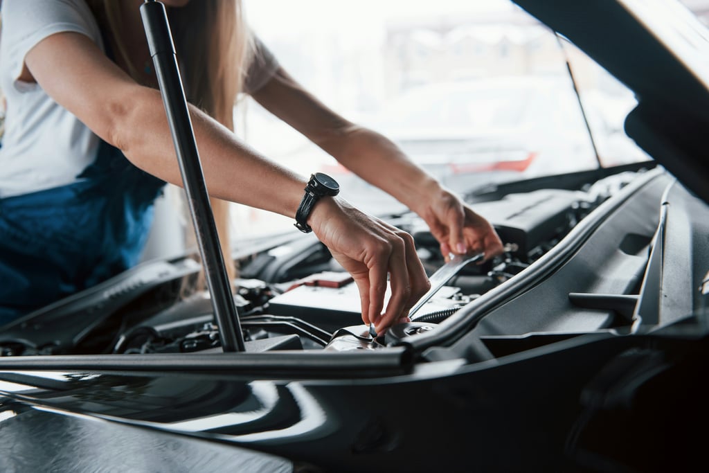 Person working on a car engine with a wrench.
