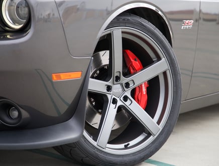 Close-up view of a car wheel featuring a black five-spoke alloy rim, a red Brembo brake caliper, and a visible 392 HEMI badge on the vehicle's fender.